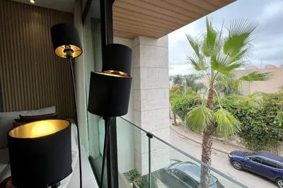 a balcony with a view of a palm tree and a car at Casa The Address - By AppartAli in Casablanca