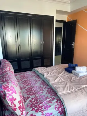 a bedroom with a bed with a pink blanket and black cabinets at Furnished apartment in the middle of the city in Casablanca