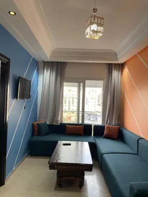 a living room with a blue couch and a table at Furnished apartment in the middle of the city in Casablanca