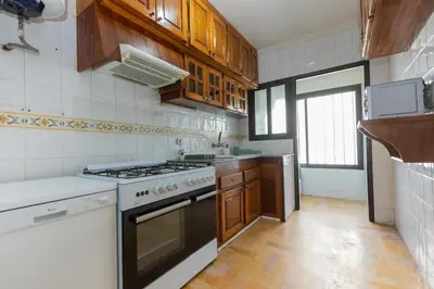 a kitchen with wooden cabinets and a stove top oven at 3BR Apartment in Prestigious Hay Riad by MERAT HOME in Rabat
