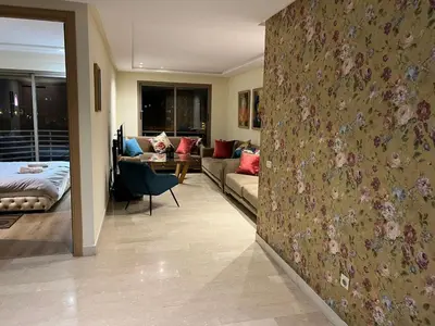 a room with a couch and a living room with a wall with flowers at Appartement vue sur le phare in Casablanca