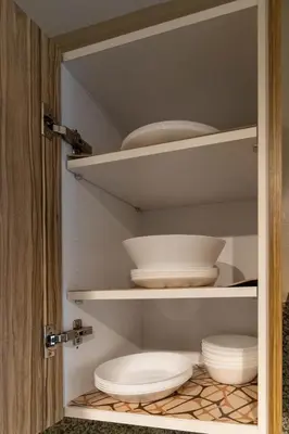 a cupboard with white bowls and plates in it at Appartement élégant a Parc Mohammedia - proche de la mer in Mohammedia