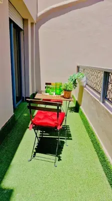 a table and a red chair on a balcony at Fundays Stay Casablanca in Casablanca