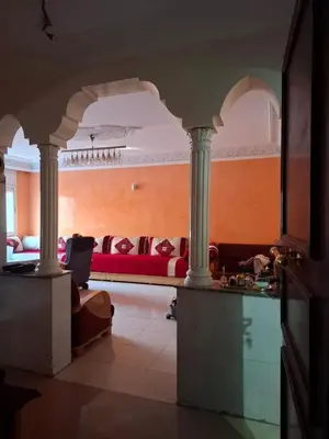 a living room with a red couch and columns at Appartement Chahdia in Casablanca
