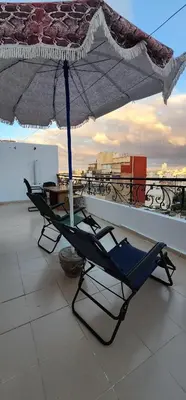 a chair under an umbrella on a roof at Privat Room in a Shard Apartment next to MOSQUÉE HASSAN 2 in Casablanca