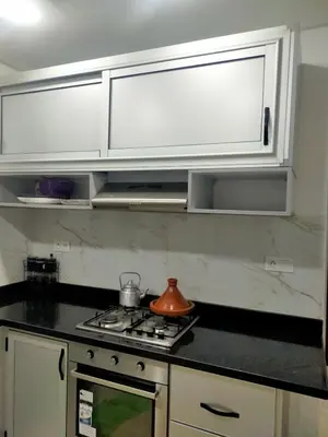 a kitchen with white cabinets and a tea kettle on a stove at Modern appt with pool and easy access to beach in Skhirat