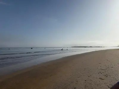 a beach with people walking in the water at Modern appt with pool and easy access to beach in Skhirat