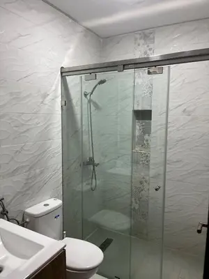 a bathroom with a shower and a toilet and a sink at Modern appt with pool and easy access to beach in Skhirat