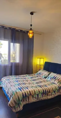 a bedroom with a bed with a colorful comforter and a window at Chic studio! Comfort and perfect location! in Rabat
