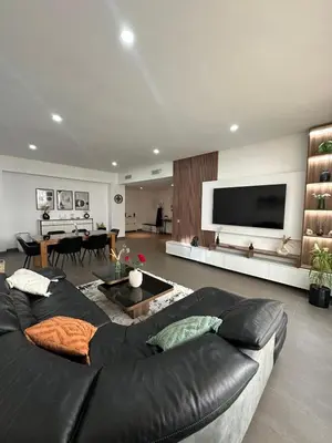 a living room with a black leather couch and a flat screen tv at Nams Casa Home in Casablanca