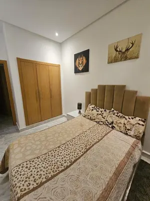 a bedroom with a large bed and a wooden door at Sables d'or flat apartement in El Harhoura