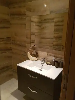 a bathroom with a sink and a wooden wall at Sables d'or flat apartement in El Harhoura