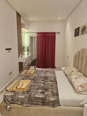 a large bed in a room with a red curtain at Sables d'or flat apartement in El Harhoura