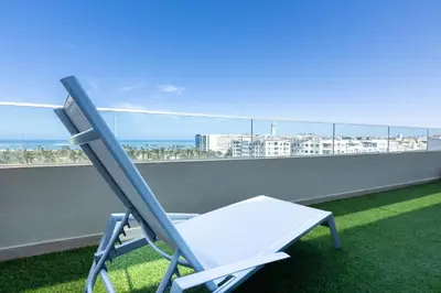 a chair on a balcony with a view of the ocean at Homerest appartement Casablanca in Casablanca