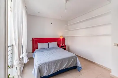 a bed with a red headboard in a white bedroom at Villa Zen, piscine privée et plage in Casablanca