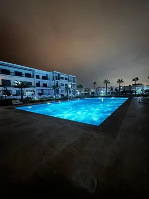 a large swimming pool in front of a building at night at Jolie appartement bord de mer de standing in Mohammedia