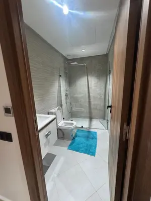 a bathroom with a toilet and a blue rug at Jolie appartement bord de mer de standing in Mohammedia