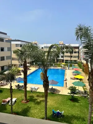 a view of a pool with palm trees and umbrellas at Beautiful Family Apartment Beach Paradise Residence in Pont Blondin