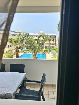 a table and chairs with a view of a pool at Beautiful Family Apartment Beach Paradise Residence in Pont Blondin