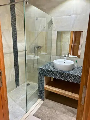 a bathroom with a sink and a glass shower at Beautiful Family Apartment Beach Paradise Residence in Pont Blondin