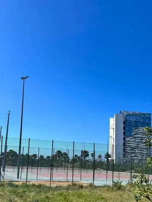 a tennis court behind a fence with a building at Charming Apartment Residence Ocean Park Pool, Sea in Aïn Harrouda