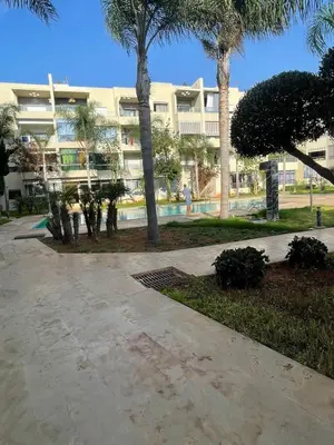 a large building with palm trees in front of it at Bel appartement à proximité plage avec piscine in Pont Blondin