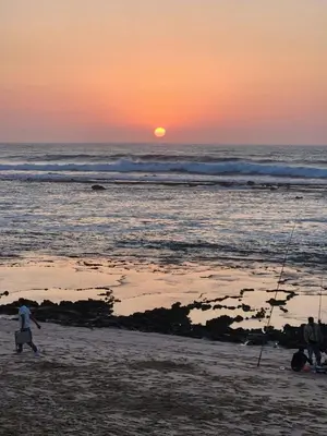 a group of people walking on the beach at sunset at Joumaira beach in Temara