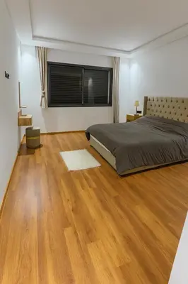 a bedroom with a bed and a wooden floor at Jolie appartement piscine bord de mer Haut standing in Mansouria