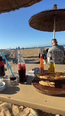 a table with food and drinks on the beach at Jolie appartement piscine bord de mer Haut standing in Mansouria