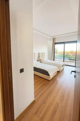 two beds in a room with a window at Jolie appartement piscine bord de mer Haut standing in Mansouria