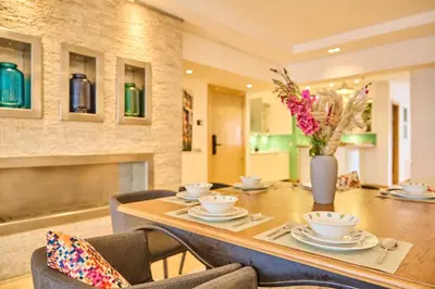 a dining room with a table with chairs and a vase of flowers at Gauthier Pearl - Luxury 3BR Apartment in Casablanca