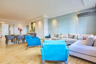 a living room with a white couch and blue chairs at Gauthier Pearl - Luxury 3BR Apartment in Casablanca