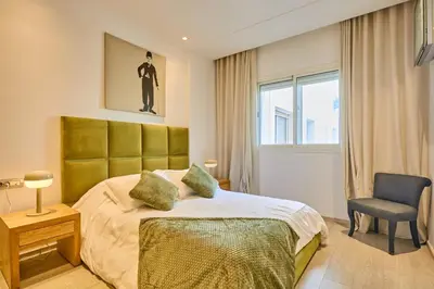 a bedroom with a large bed and a chair at Gauthier Pearl - Luxury 3BR Apartment in Casablanca