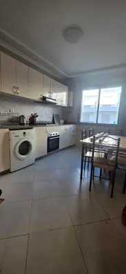 a kitchen with a washing machine and a table and chairs at appartement a louer sable d'or mansouria in Pont Blondin