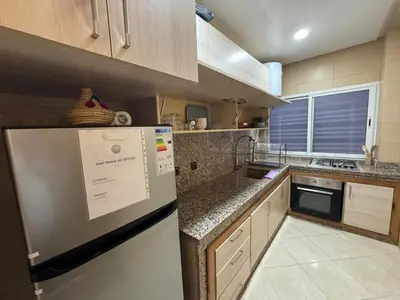 a small kitchen with a refrigerator and a sink at bel appartement in Temara