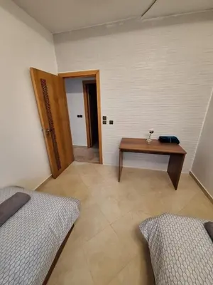 a room with two beds and a wooden table at bel appartement in Temara