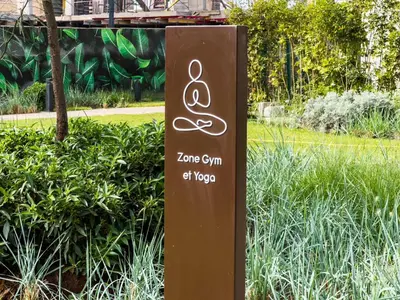 a sign in the middle of a garden at Cozy Studio with Pool & Parking in Aïn Harrouda