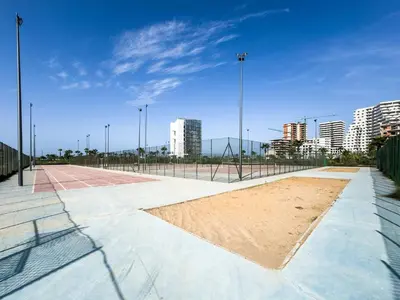 an empty tennis court in a city with tall buildings at Cozy Studio with Pool & Parking in Aïn Harrouda