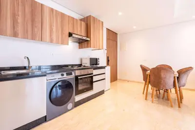 a kitchen with a stove and a dishwasher and chairs at Cozy Studio with Pool & Parking in Aïn Harrouda