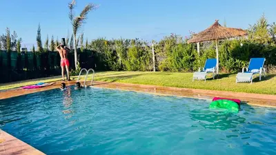 a man standing on the edge of a swimming pool at Ferme royale Bensliman in O Ben Slimane