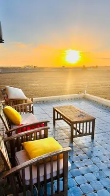 a sunset over the ocean with chairs and a table at Ferme royale Bensliman in O Ben Slimane