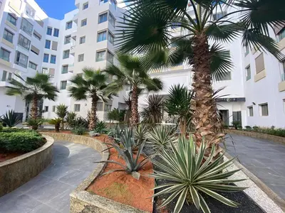a courtyard with palm trees in front of a building at Corniche Casablanca - Kimberly Luxury Suite in Casablanca