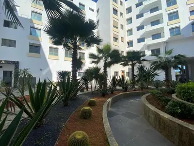 a courtyard with palm trees in front of a building at Corniche Casablanca - Kimberly Luxury Suite in Casablanca