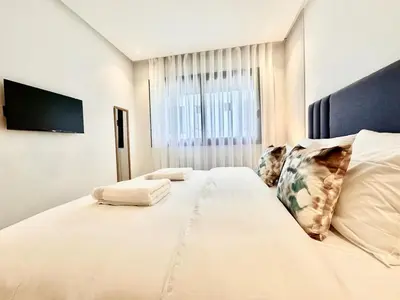 a large white bed in a room with a window at Cozy, Elegant Apartment, Parking and Fiber in Casablanca