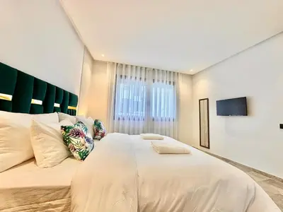 a bedroom with a large white bed and a window at Oasis Studio - Parking, Fiber, Near the Station in Casablanca