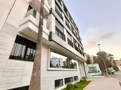 a white building with a palm tree in front of it at Oasis Studio - Parking, Fiber, Near the Station in Casablanca