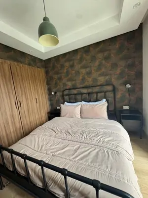 a bed in a bedroom with a brick wall at Studio Zenata Central Park Près de la plage Vue Piscine in Aïn Harrouda