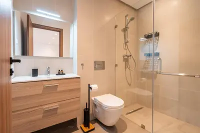 a bathroom with a shower and a toilet and a sink at Modern Apartment Pool Balcony & Comfort in Aïn Harrouda