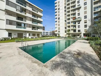 a swimming pool in front of two tall buildings at Modern Apartment Pool Balcony & Comfort in Aïn Harrouda