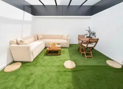 a living room with a white couch and green carpet at MAYA SUITES - Corniche Seaside in Casablanca